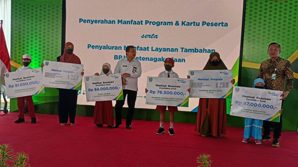 Depdir BPJS Ketenagakerjaan Jatim Hadi Purnomo dan Asisten I Sekda Jatim Benny Sampirwanto saat menyerahkan manfaat program dan beasiswa, Rabu (25/1/2023)