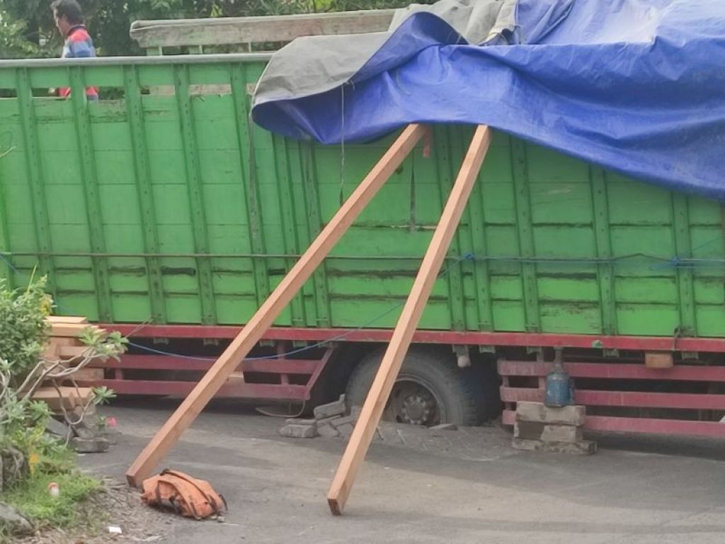 Ban yang amblas menghancurkan paving dan truk harus ditopang kayu agar tidak roboh.