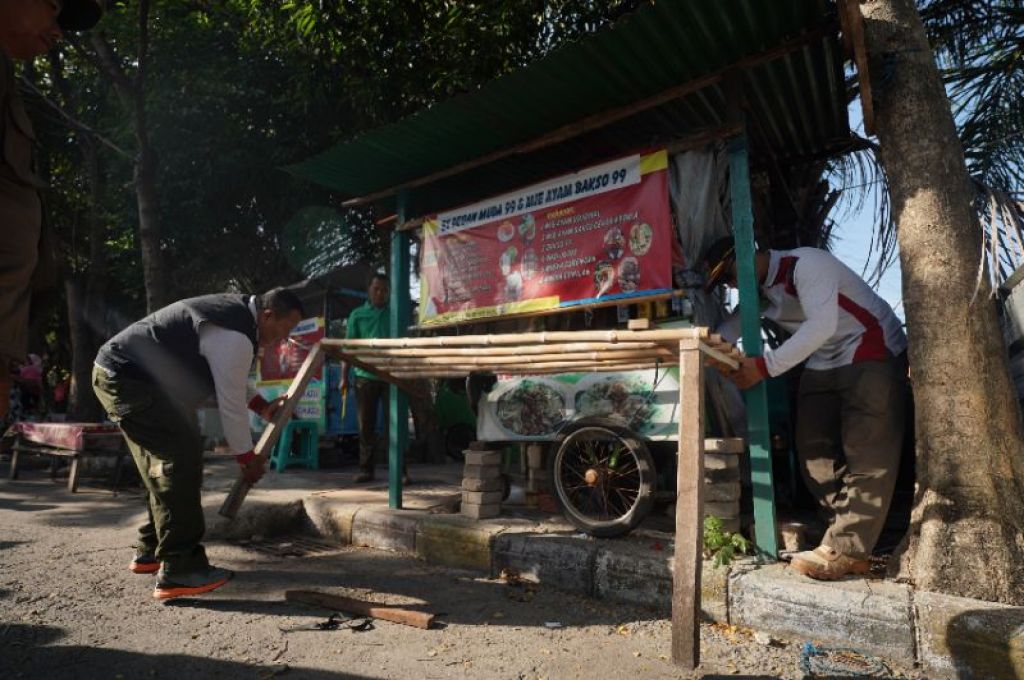 Lapak yang dianggap kumuh dibongkar oleh petugas.